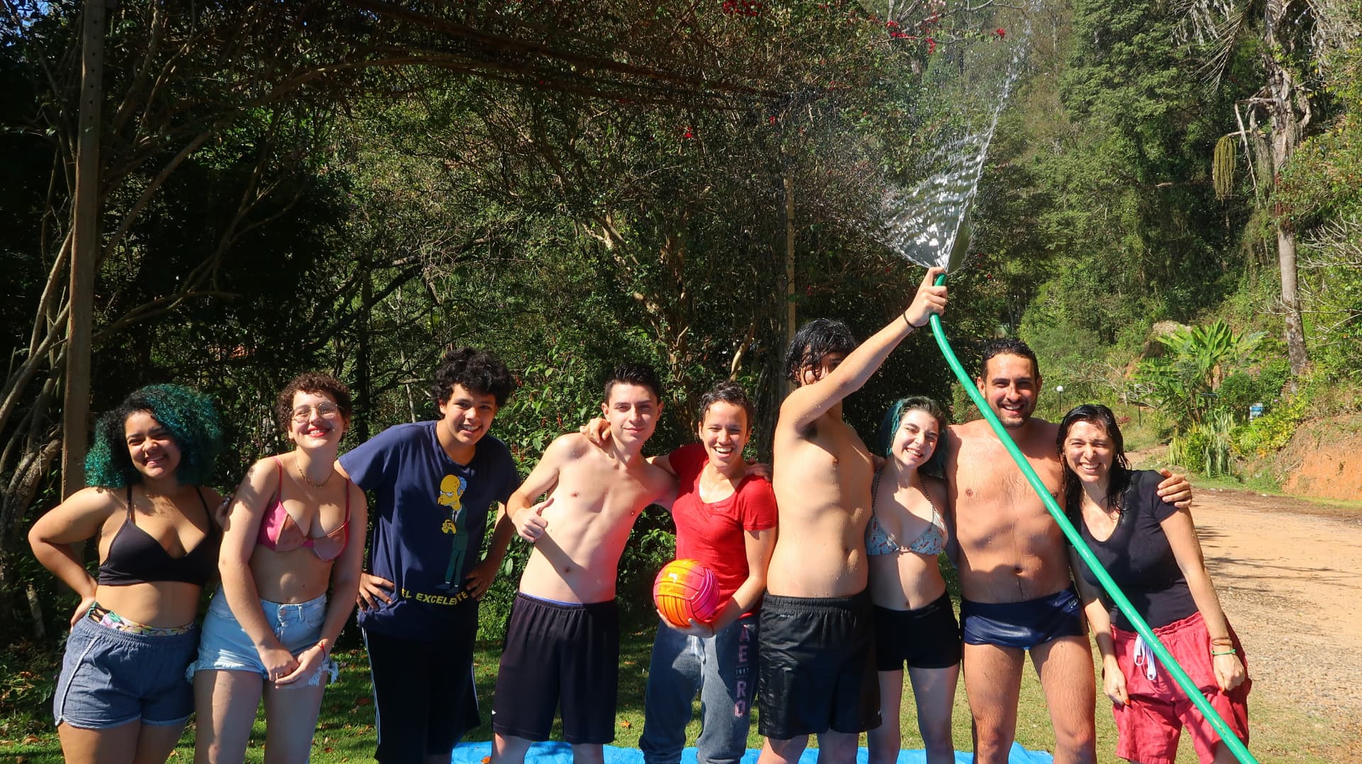 Grupo de jovens sorrindo juntos na brincadeira com mangueira